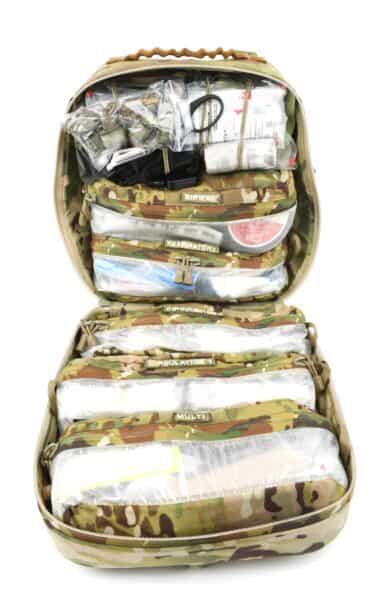 Open camouflage-patterned medical kit designed for tactical rescue training, featuring transparent pouches with bandages and scissors.