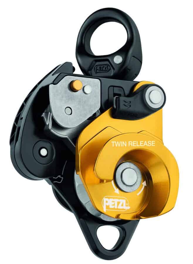 This image shows a Petzl Twin Release pulley device with black and orange components, perfect for tactical rescue training or technical climbing.