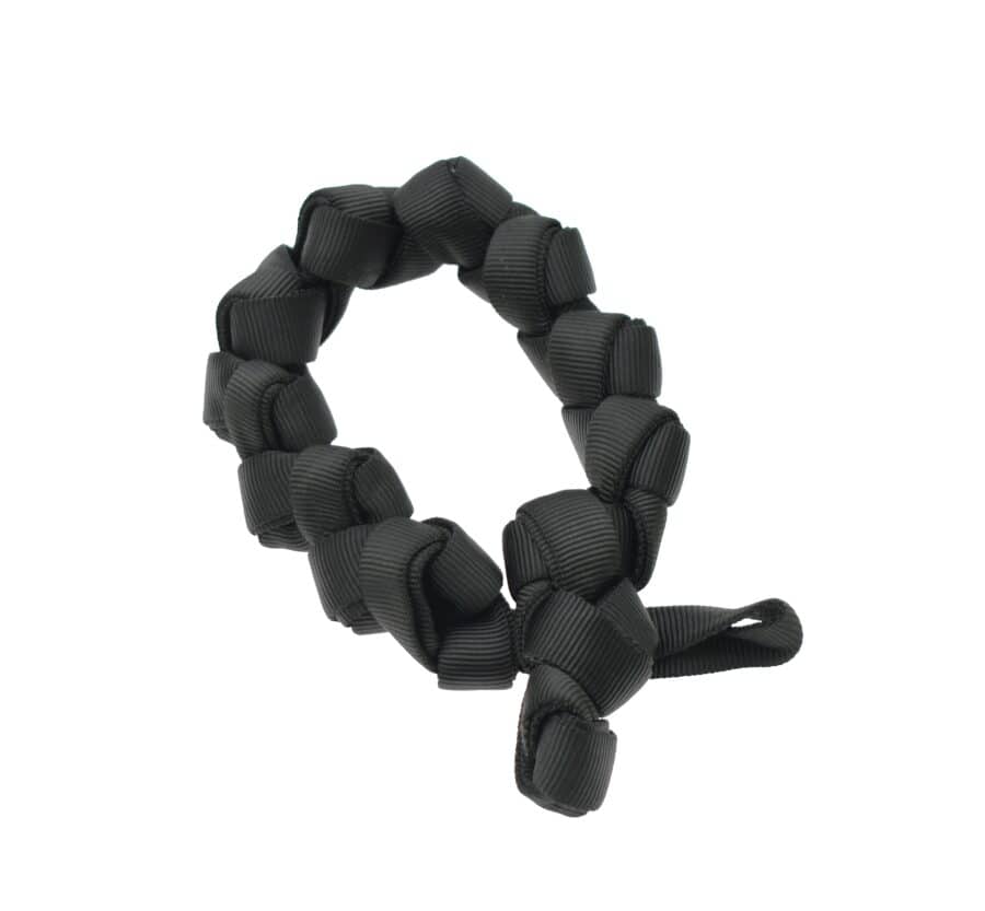 A black scrunchie, made of twisted ribbon material, arranged in a circular shape, resembles the rugged form of industrial rescue equipment.